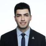 Professional headshot of a man in a suit and tie against a plain background.